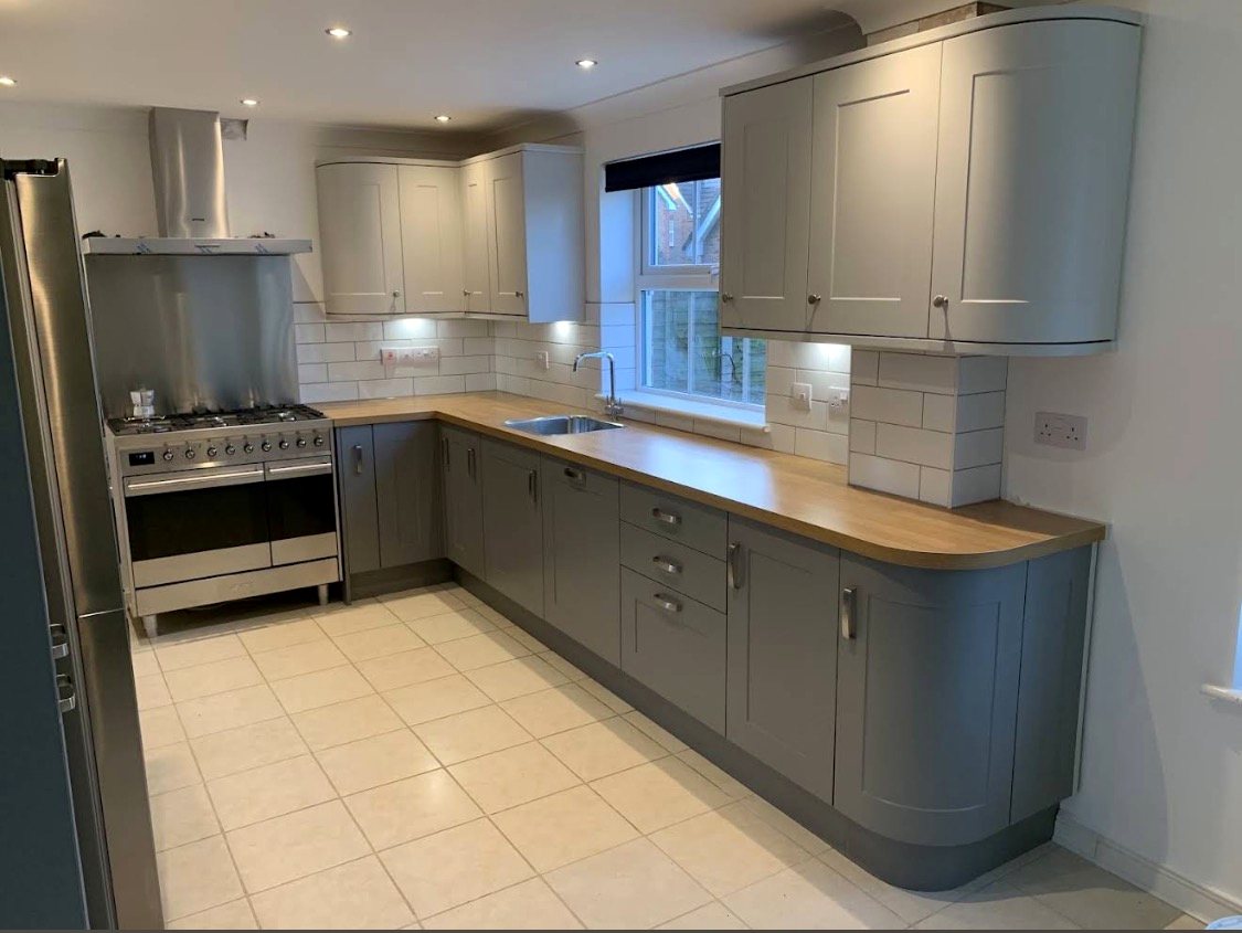 Two-tone shaker kitchen with range cooker, oak worktops and curved units